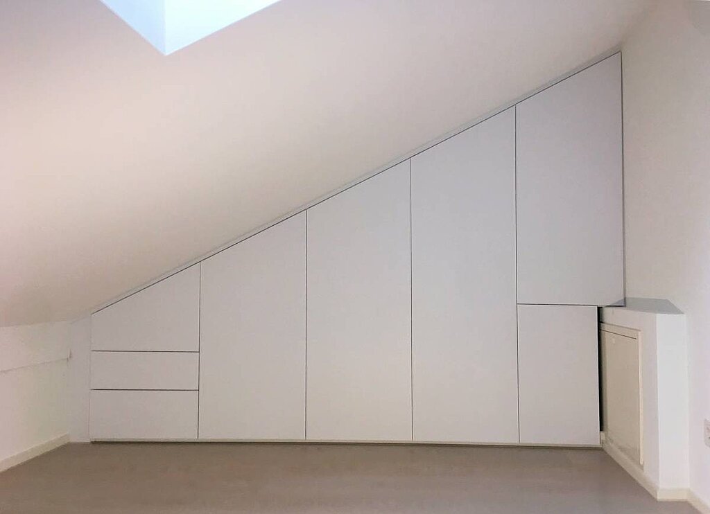 Ein perfekt eingepasster Einbauschrank unter der Dachschräge mit ausgesparter Ecke für den Vorsprung. Das gelingt nur mit einem millimetergenauen Aufmaß - und auch das gehört zu unserem Rundum-Service.