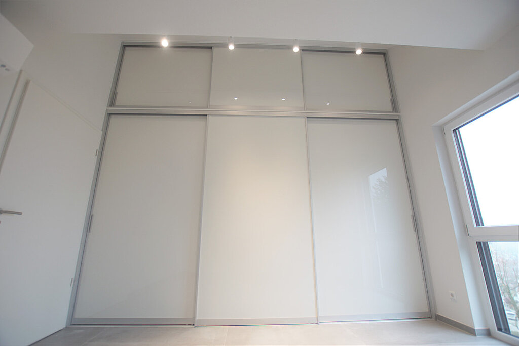 Unser Kunde aus Reutlingen hat sich Stauraum über die komplette Wand gewünscht. Dabei sollte es unauffällig und schlicht werden. Das Ergebnis: Ein maßgefertigter Einbauschrank mit weißen Schiebetüren, der Platz für die gesamte Garderobe schafft.