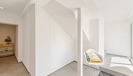 Weiße Flurgarderobe unter Dachschräge, maßgefertigt für optimalen Stauraum.