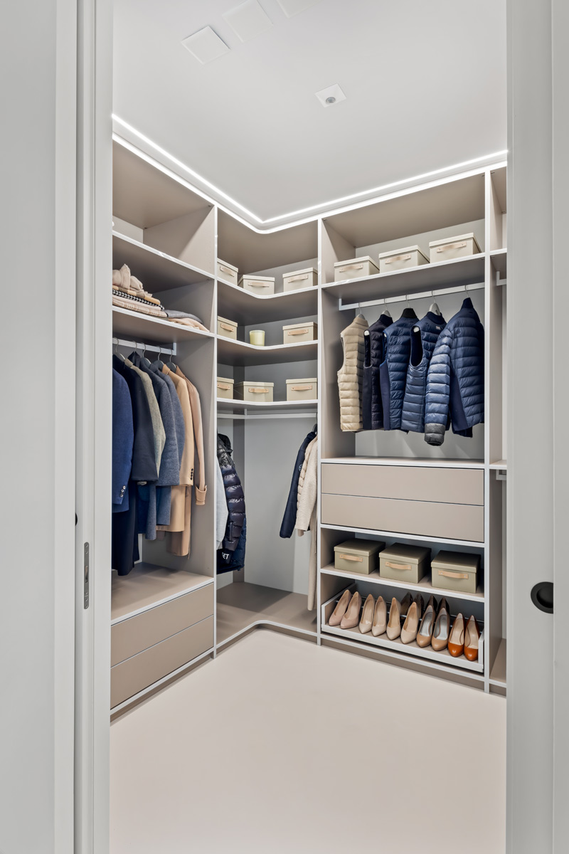 Seitenansicht einer offenen Ankleide in beige mit Schuhregal und Schubladen