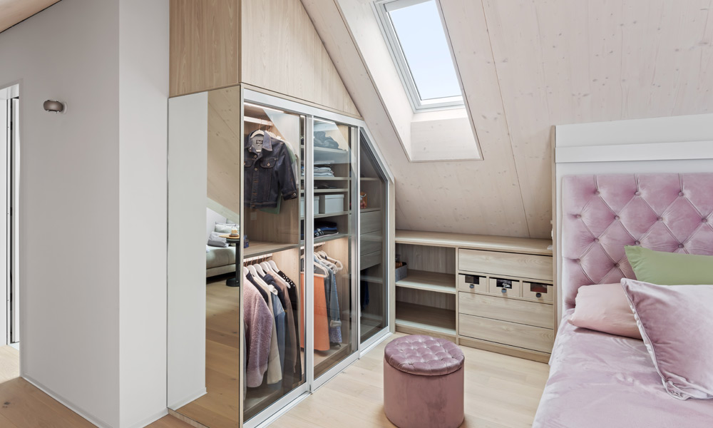 Moderner Schiebetürenschrank mit Glastüren unter einer Dachschräge verbaut