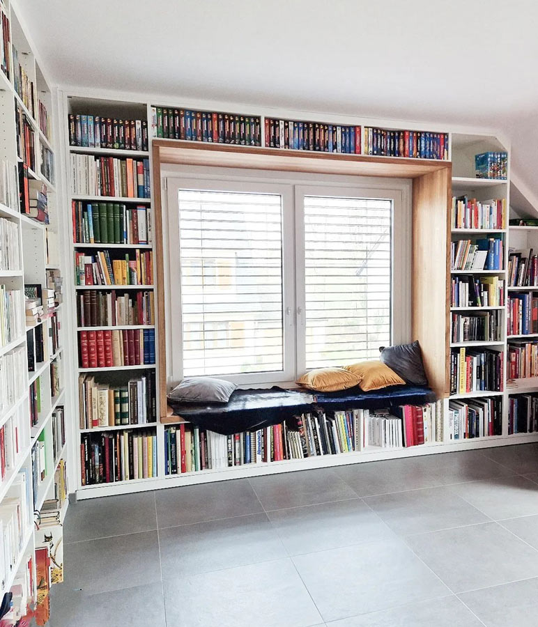 Bücherregal mit Fensteraussparung, sodass diese als Leseecke dient