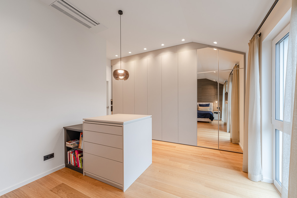 Einbauschrank im Schlafzimmer für eine Dachschräge mit grauen Fronten und integriertem Spiegel