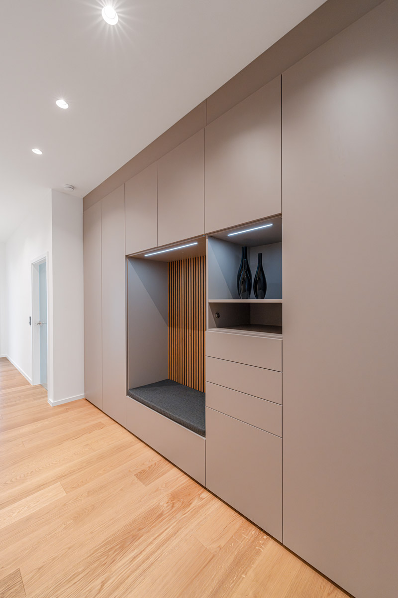 Stilvolle Flurgarderobe mit Akustikpaneelen als Rückwand und einer Sitzbank, die modernen Komfort und Design kombiniert.