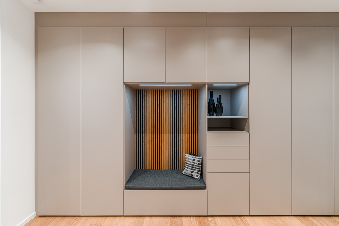 Beige Flurgarderobe mit integrierter Sitzbank und Akustikpaneelen als stilvolle Rückwand im Eingangsbereich.