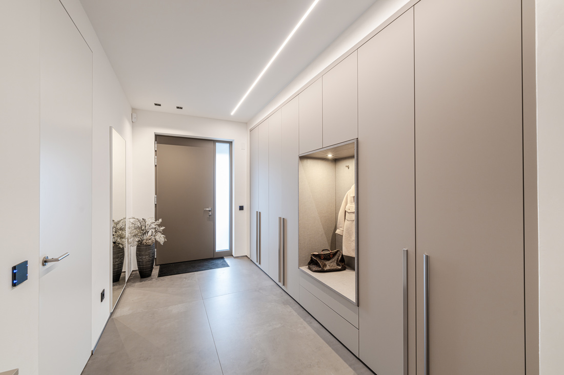 Moderne Flurgarderobe mit grauer Sitzbank und zusätzlichem Stauraum, perfekt für einen organisierten und eleganten Eingangsbereich.