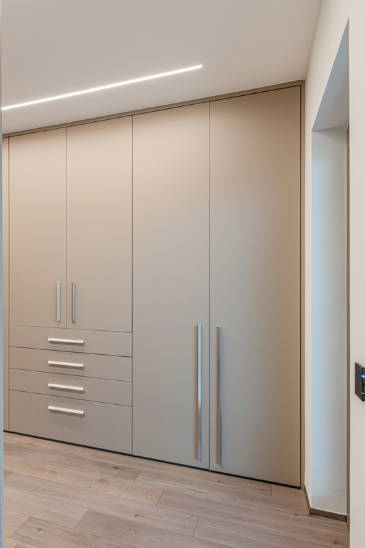 moderner maßgefertigter Nischenschrank mit silbernen Griffen im Wohnzimmer verbaut