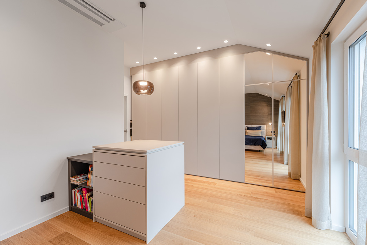 Grauer Dachschrägenschrank für das Schlafzimmer mit passender Insel und integriertem Spiegel