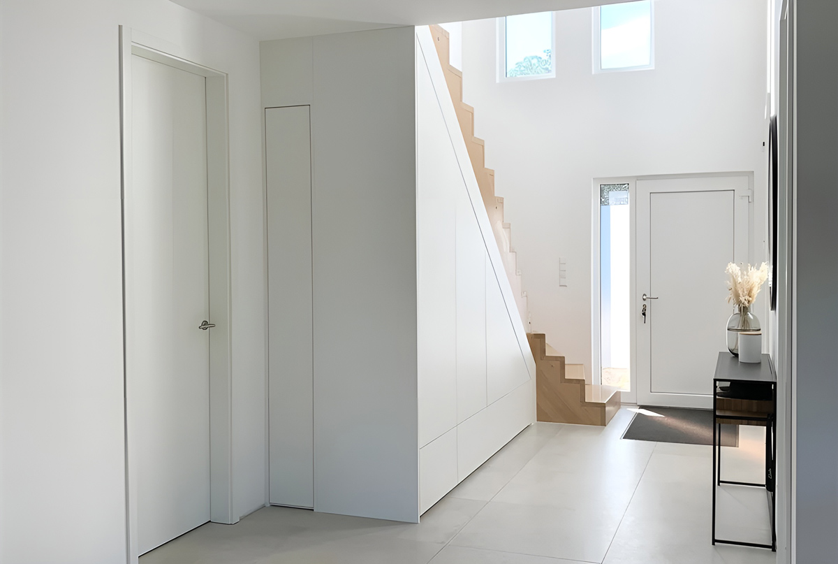 weißer Treppenschrank nach Maß in einem minimalistischen Eingangsbereich