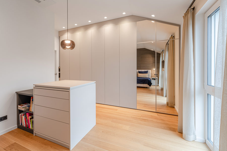 Schlafzimmer mit grauem Wandschrank unter einer Dachschräge verbaut mit passender Insel im selben Dekor